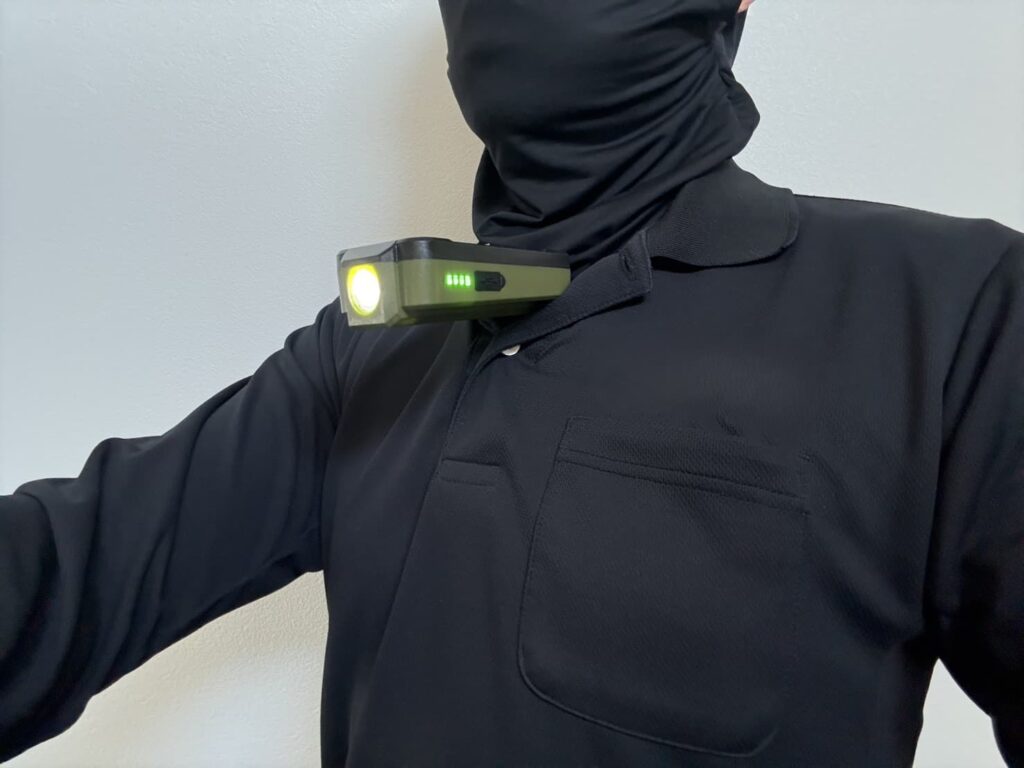 黒いポロシャツの胸元にアストロプロダクツの作業灯をボタン部分に引っ掛けて装着している様子