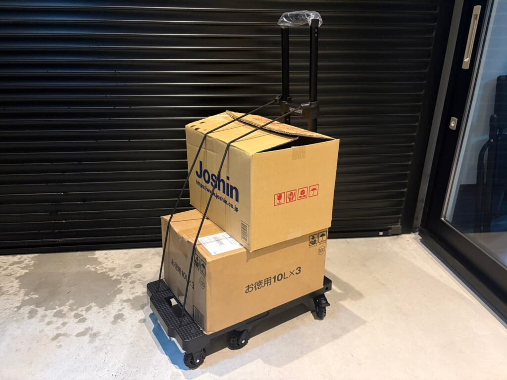 荷物を2箱載せてゴムバンドで固定した折りたたみ台車